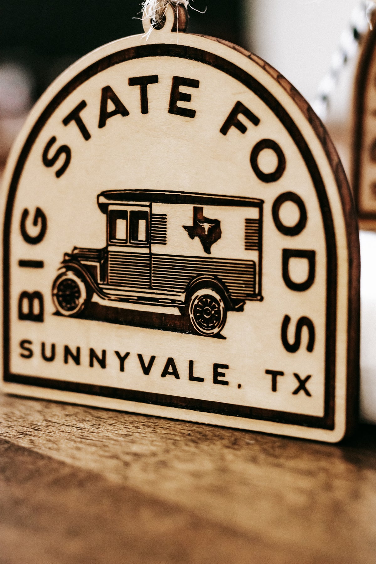 Close-up of round wooden ornament showing van graphic with “Sunnyvale, TX” at bottom.