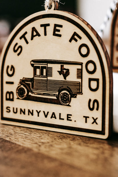 Close-up of round wooden ornament showing van graphic with “Sunnyvale, TX” at bottom.