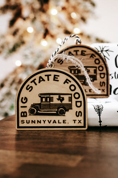 Wooden hanging ornament with van illustration and “Big State Foods, Sunnyvale, TX”.