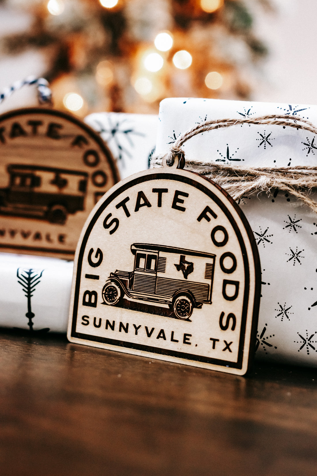 Wood arched state logo ornament with engraved bus and starburst patterns, twine loop