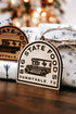 Wood arched state logo ornament with engraved bus and starburst patterns, twine loop