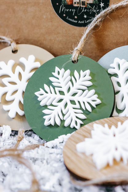 Layered round wooden snowflake ornaments: green and natural wood with white snowflake details, twine