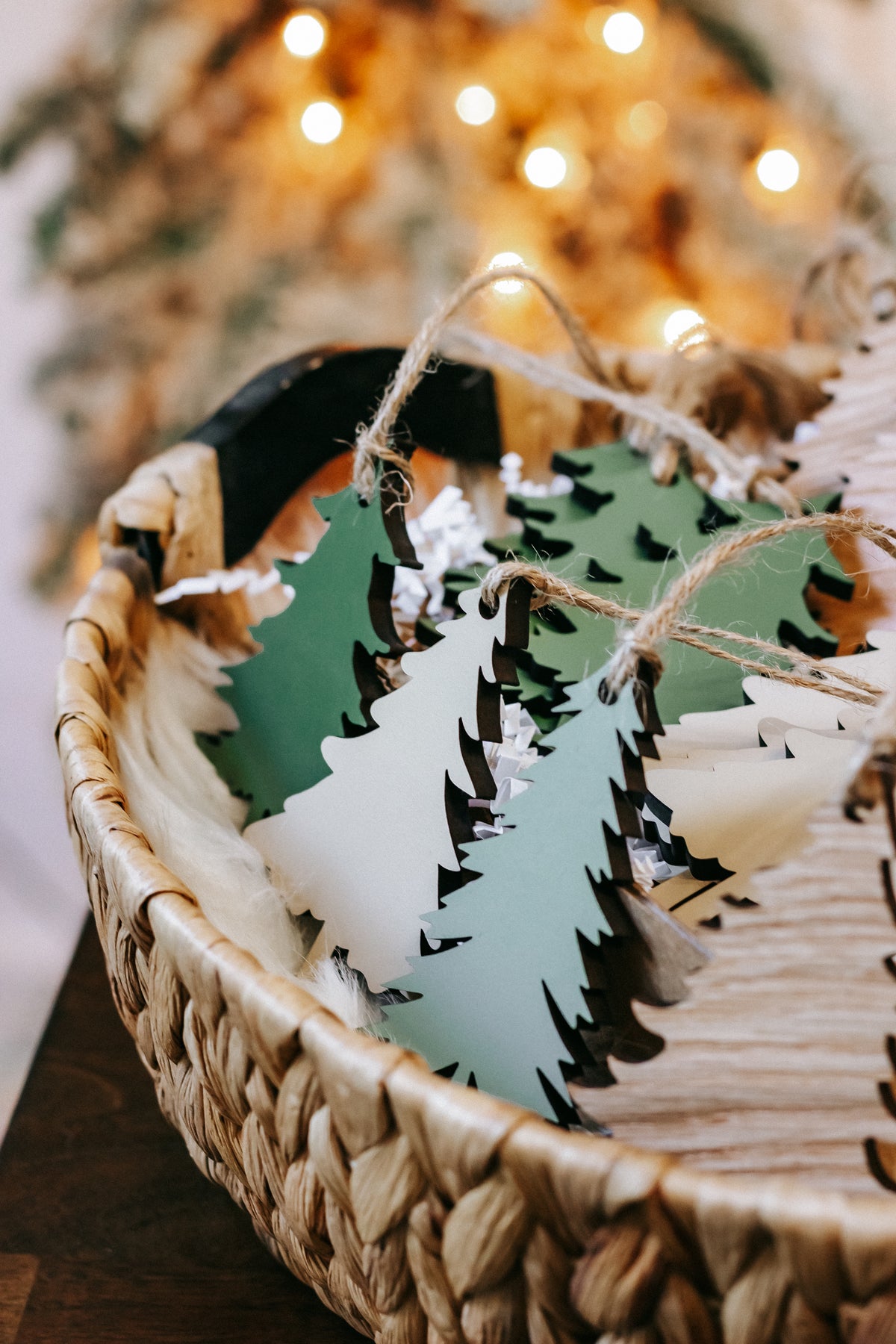 Wooden Christmas tree ornaments in green and natural wood lying in a woven basket