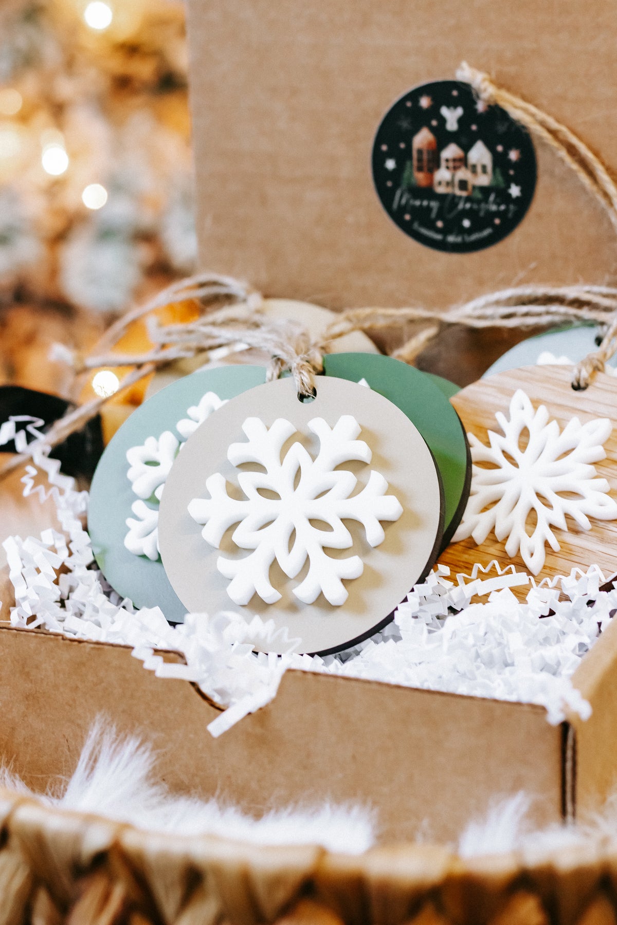 Round wooden snowflake ornaments on twine hangers, green and natural bases with white cutouts