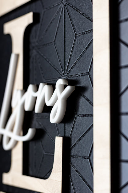 Rectangle family name sign corner detail with white cursive letters over dark geometric texture
