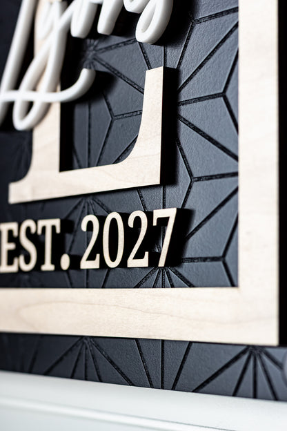 Rectangle family name sign detail with "EST. 2027" text and white cursive letters on dark panel