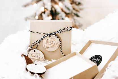 Cardboard gift box with two round engraved wood ornaments tied with twine
