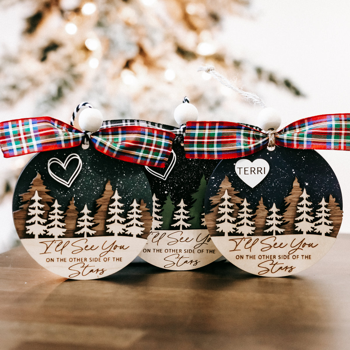 Memorial Christmas ornaments with plaid bows and name TERRI, featuring pine trees and starry background.