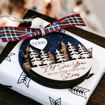 Memorial Christmas ornament with plaid ribbon and heart tag reading TERRI over pine tree scene.
