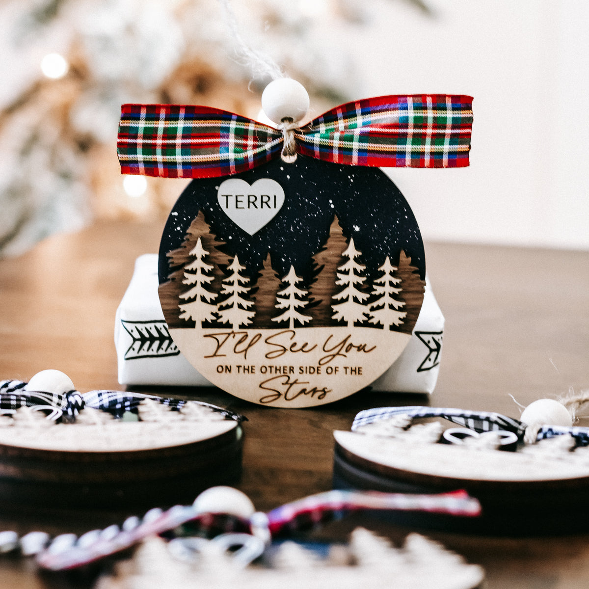 Personalized memorial Christmas ornament: pine trees, stars, and name TERRI on heart tag.