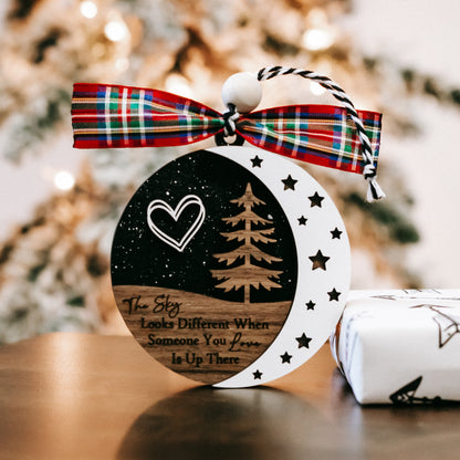 Round memorial Christmas ornament, black-and-white sky design, plaid bow, hanging loop.