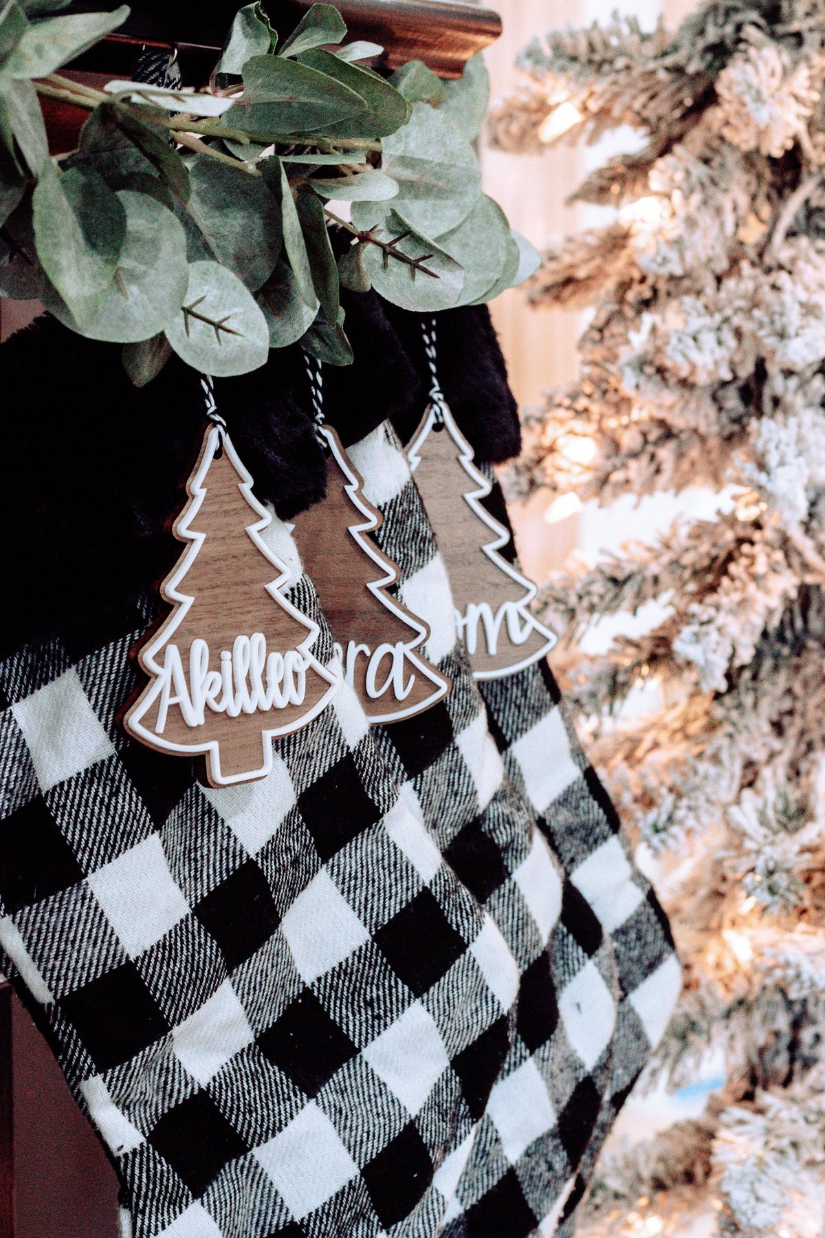 Personalized Christmas tree ornament tags hanging from buffalo plaid stocking