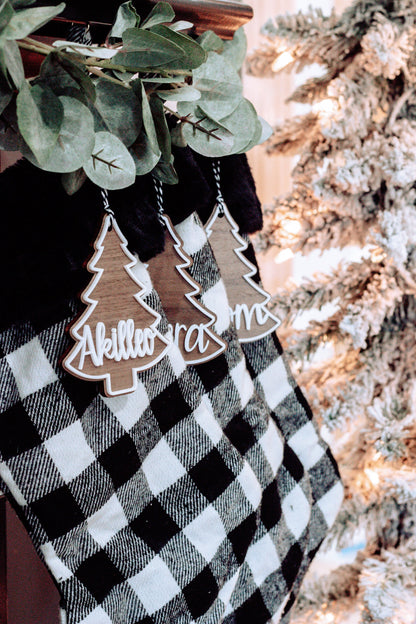 Personalized Christmas tree ornament tags hanging from buffalo plaid stocking