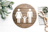 Round wood restroom sign with raised female, male, and child icons