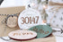 Round personalized home holiday ornament with “30147” in red on white wood.