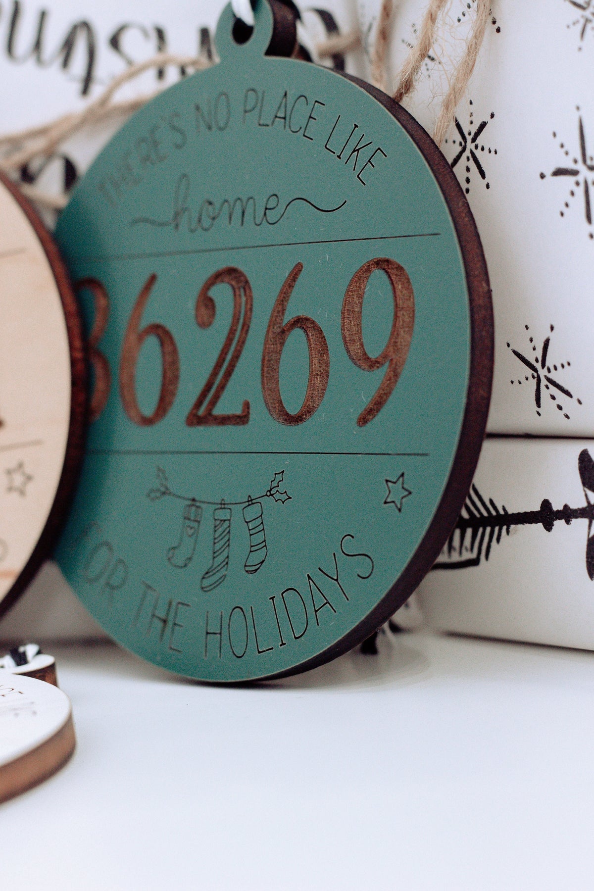 Teal round personalized home holiday ornament showing “66269” and small star icons.