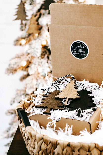 Rustic wooden Christmas tree ornament set in kraft box with hanging loops and filler.