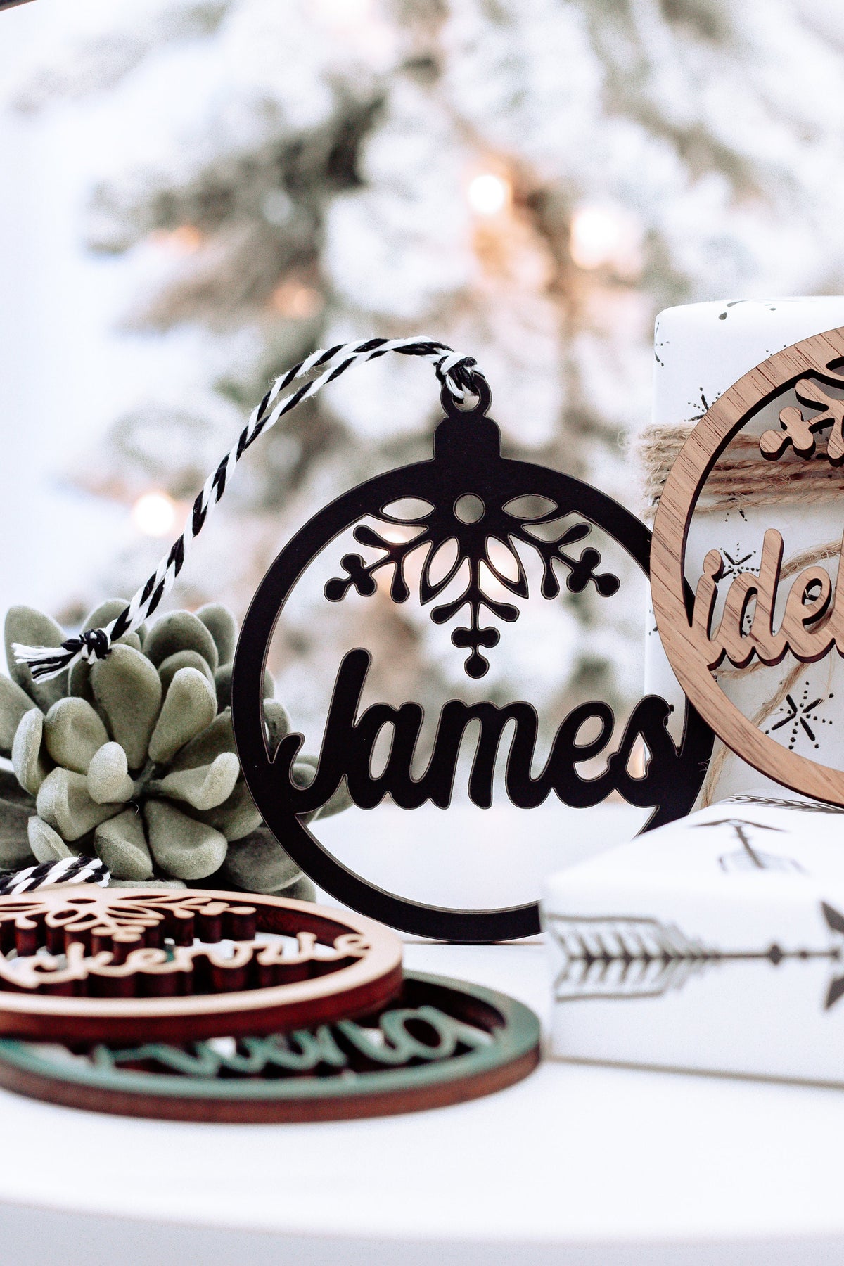Round wooden name ornament with snowflake cutout and dark lettering, on a holiday set