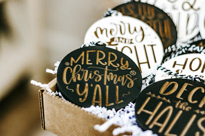 Merry Christmas engraved ornament with black background and gold script, in a gift box.