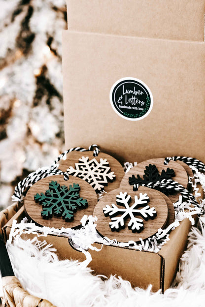 Pack of wooden snowflake ornaments with striped hangers, white, green, and dark snowflakes