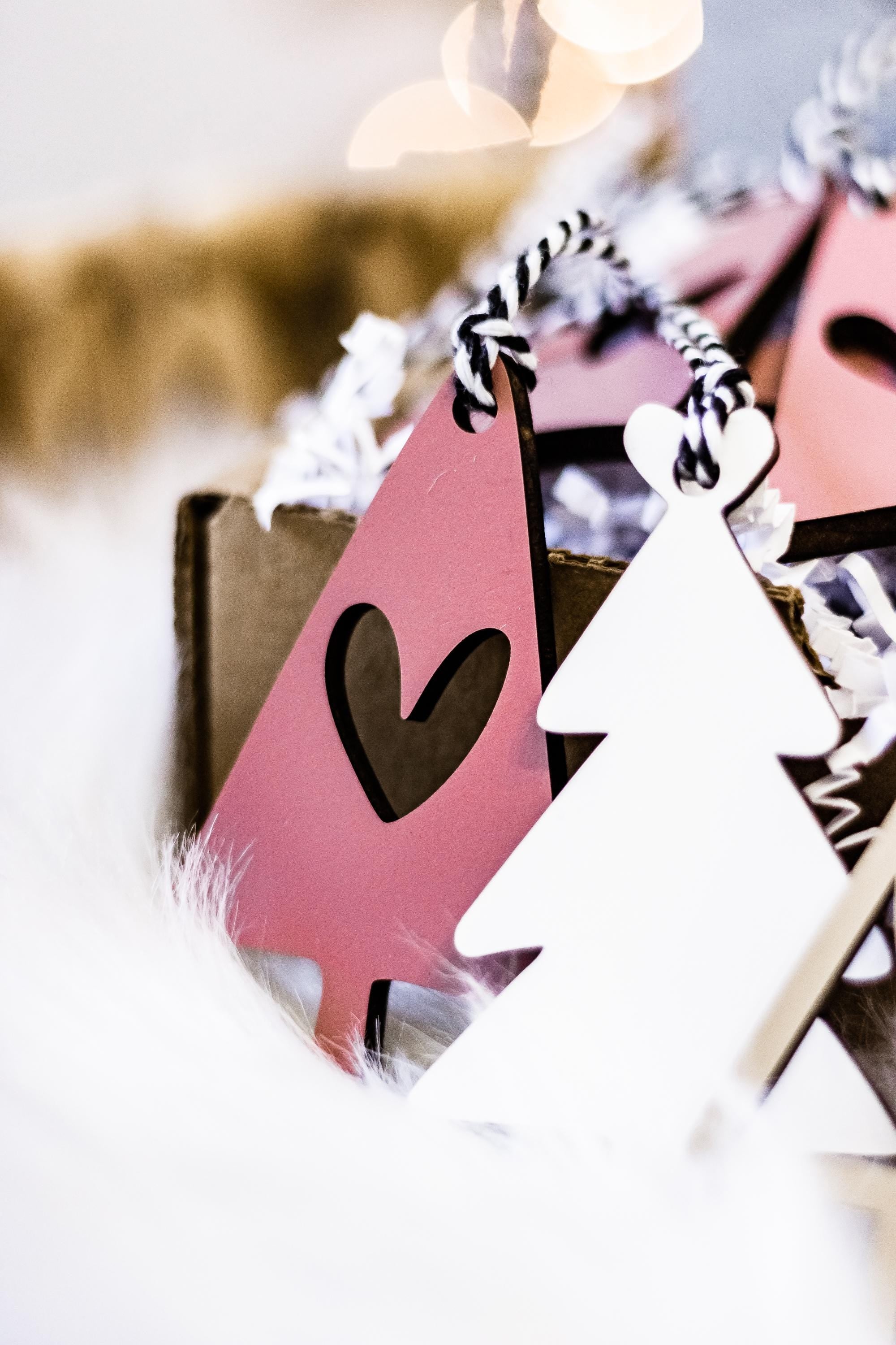 Set of wooden Christmas tree ornaments in blush pink and white with heart cutouts on loops