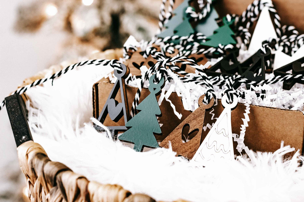 Assorted mini wooden Christmas ornaments with hanging loops, including tree and house shapes