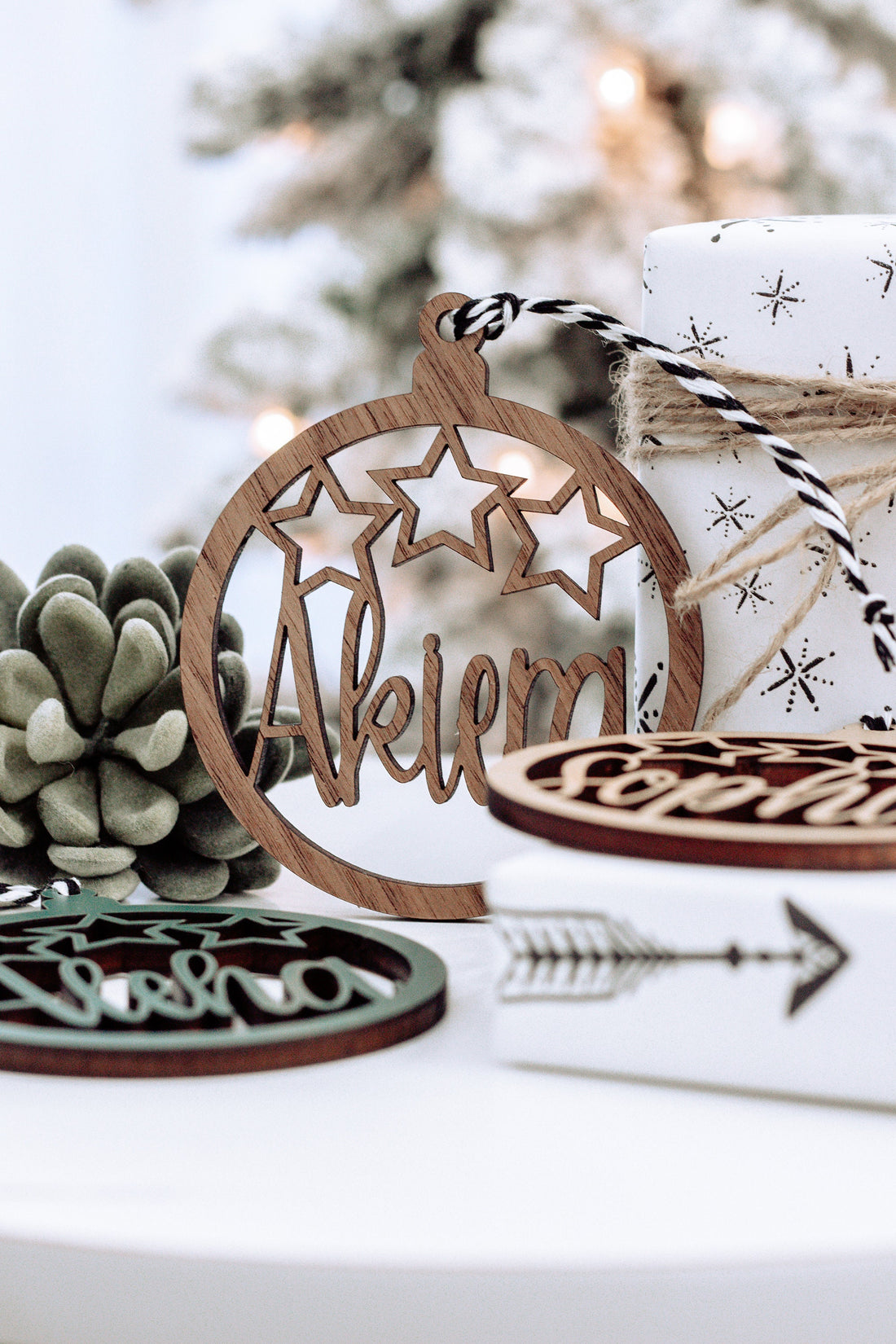 Brown wooden round name ornament with star cutouts and engraved name, tied gift