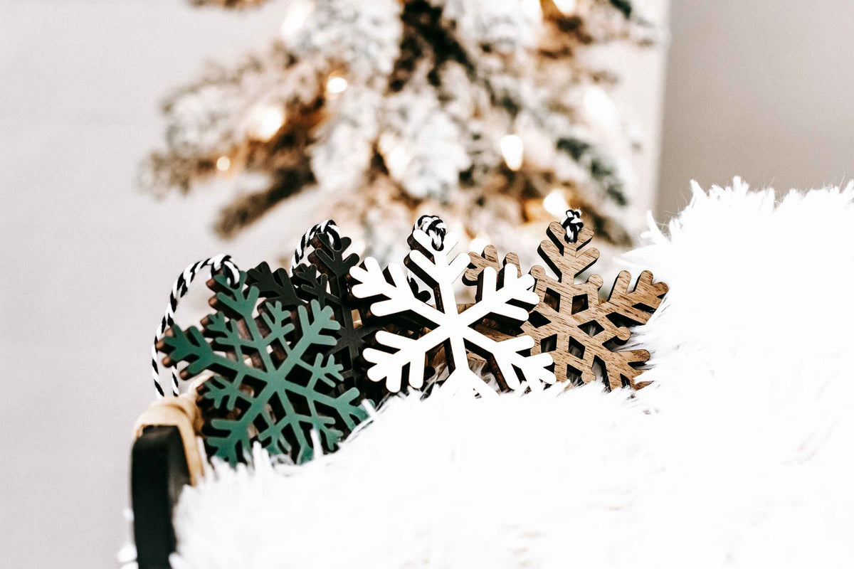 Wooden snowflake ornaments set with dark, green, white, and natural wood finishes