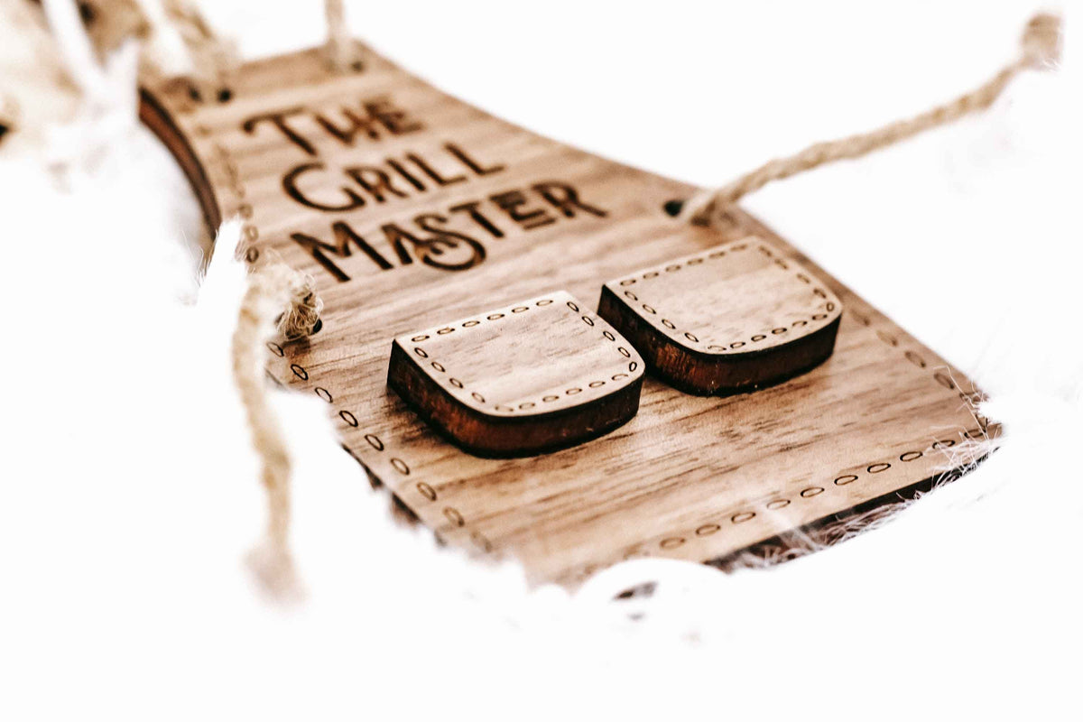 Wood grill master ornament with two grill-shaped slot pieces and “The Grill Master” text.