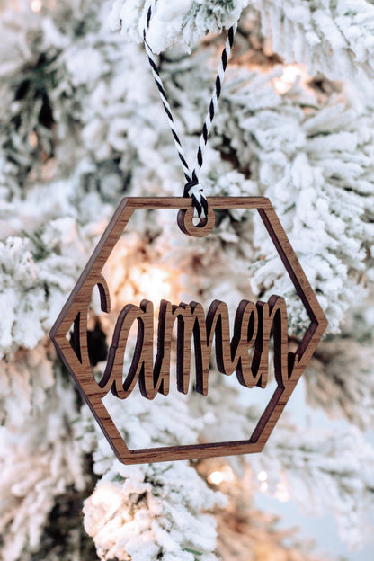 Wooden hex name ornament with cursive engraving, warm wood tone, twine loop