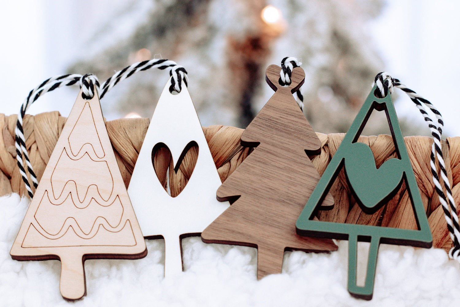 Set of wooden Christmas ornaments on snow: white trees and green tree with heart cutout