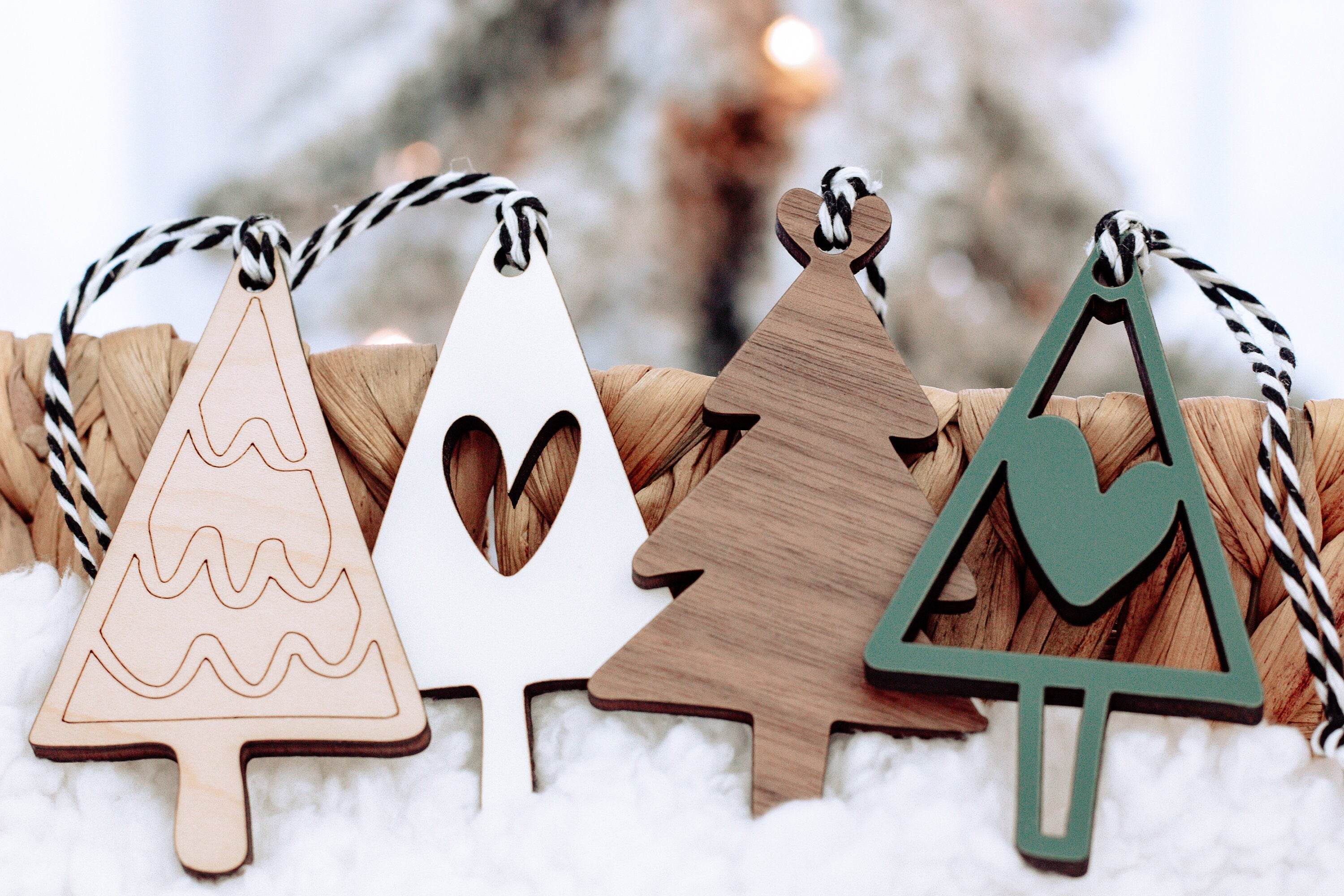 Set of wooden Christmas ornaments on snow: white trees and green tree with heart cutout