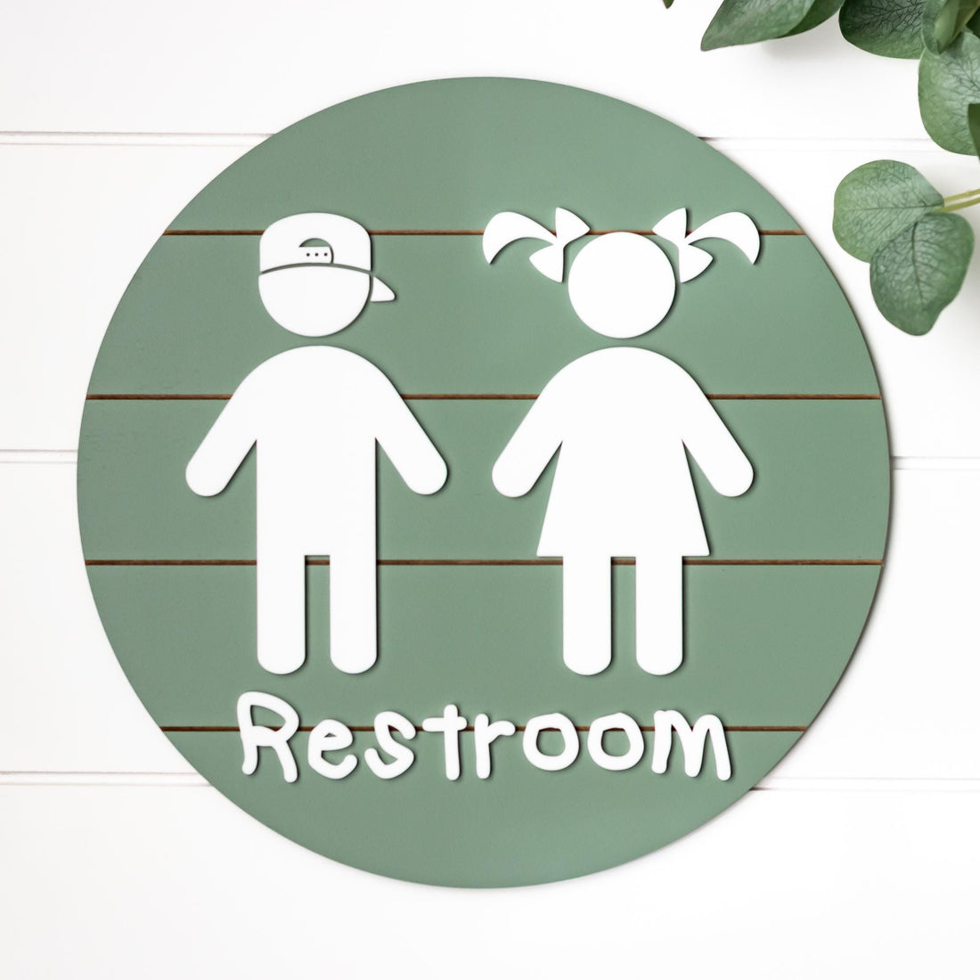 Round 3D toddler restroom sign, green with two white child figures and “Restroom”