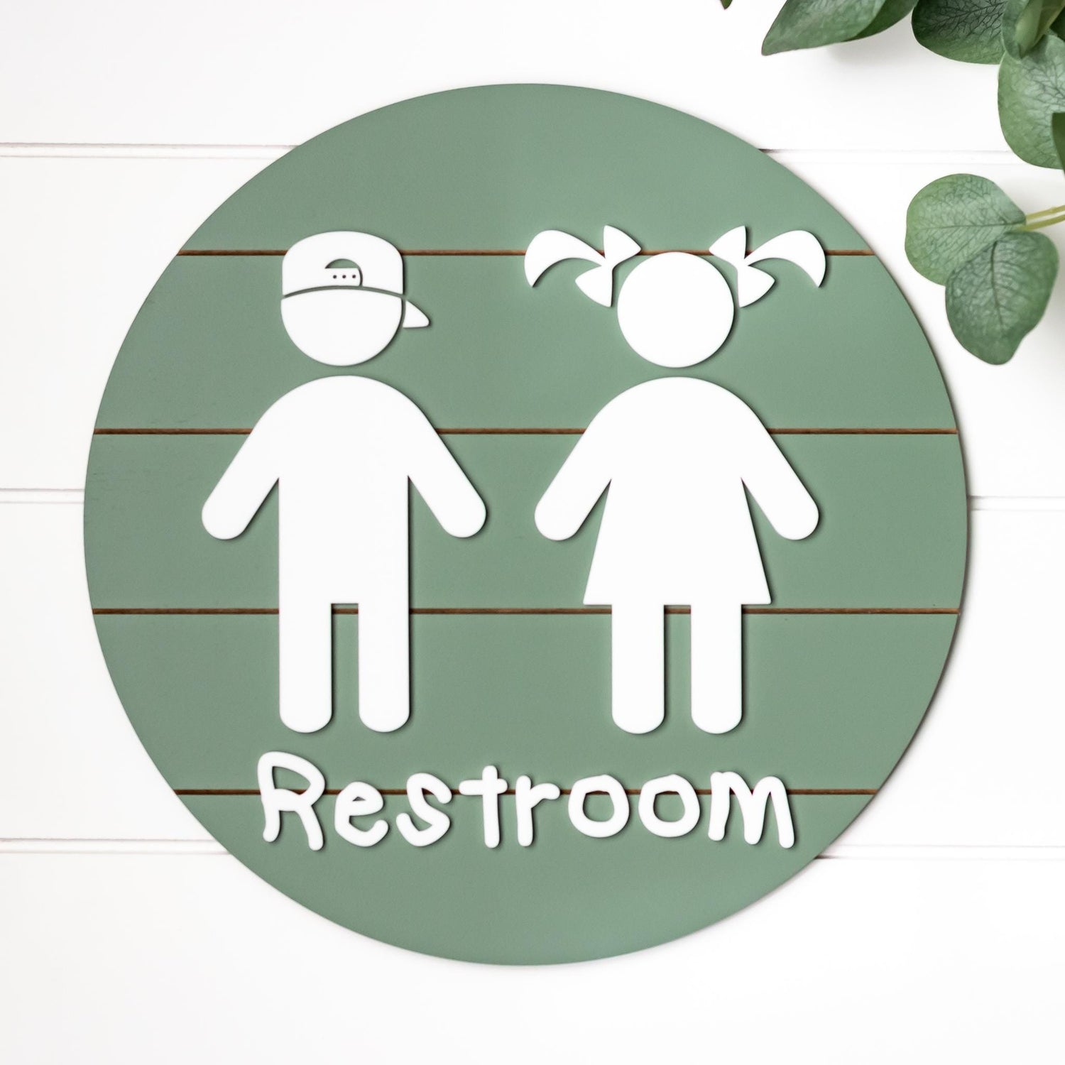 Round 3D toddler restroom sign, green with two white child figures and “Restroom”