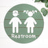 Round 3D toddler restroom sign, green with two white child figures and “Restroom”