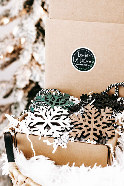 Kraft box with wooden snowflake ornaments in dark, green, tan, and white tones