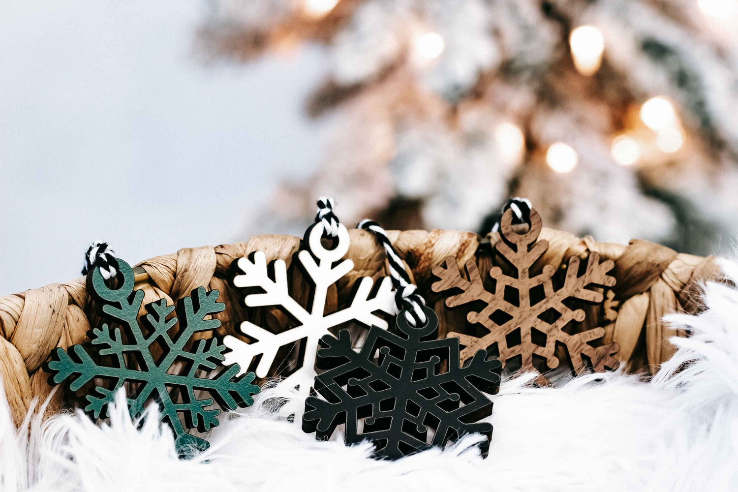 Snowflake Christmas ornaments on white faux fur, featuring black, white, teal, and tan pieces