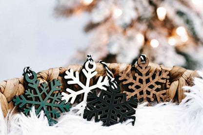 Snowflake Christmas ornaments on white faux fur, featuring black, white, teal, and tan pieces
