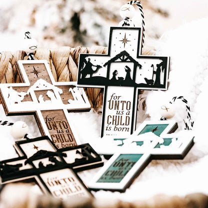 Black cross nativity ornament with star, manger silhouettes, and “for unto us a child is born”