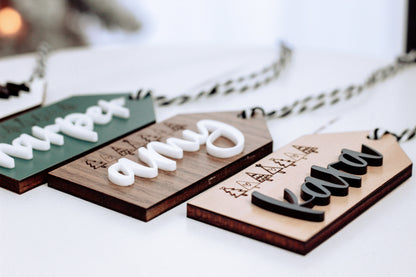 Close-up of wooden stocking tags with white raised names and Christmas tree icons.