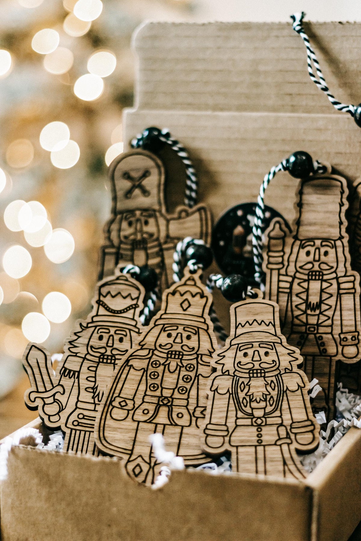 Set of 6 engraved wooden nutcracker ornaments standing in a gift box with bead cords