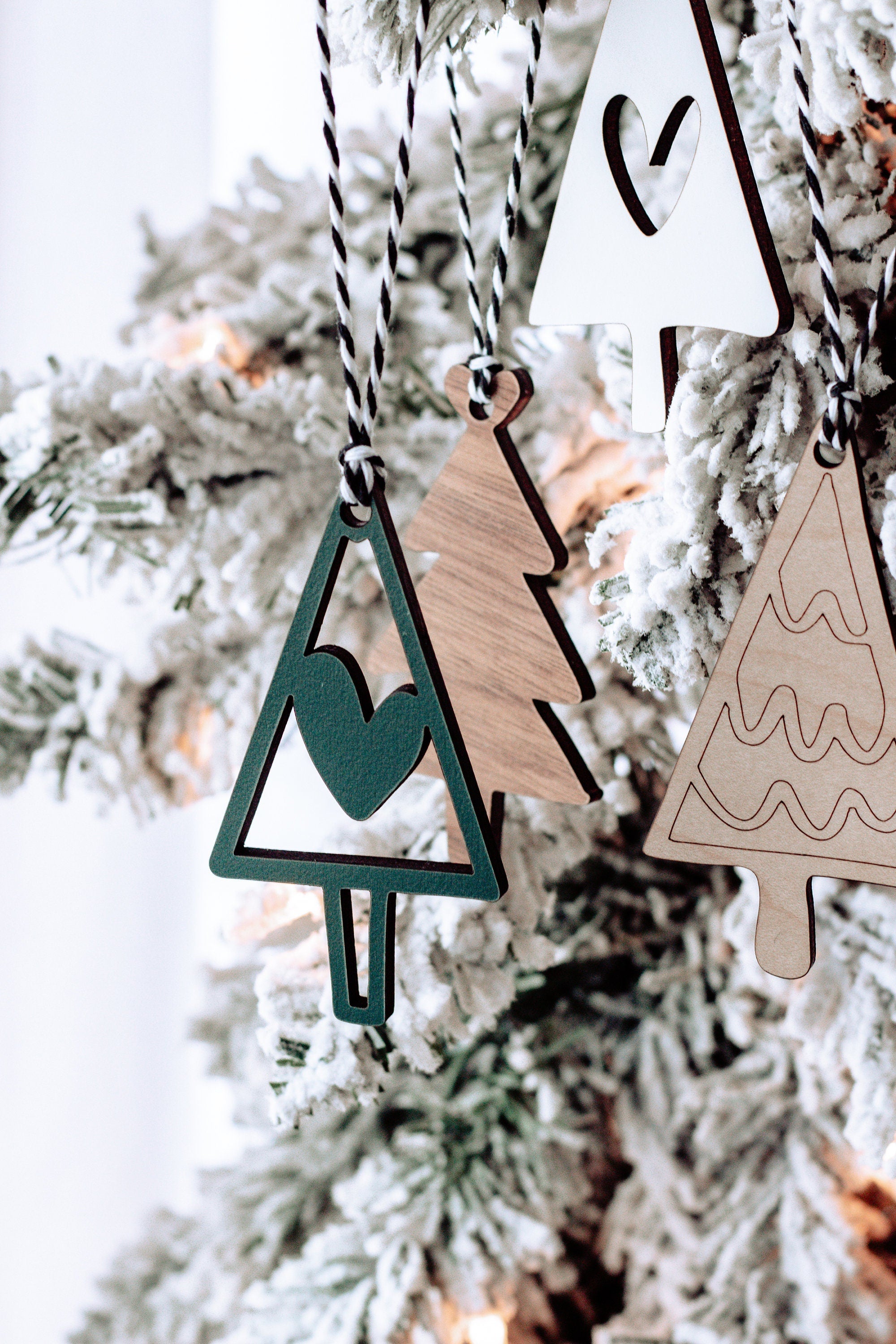 Wooden Christmas tree ornaments with striped strings; green and white designs on frosted branches