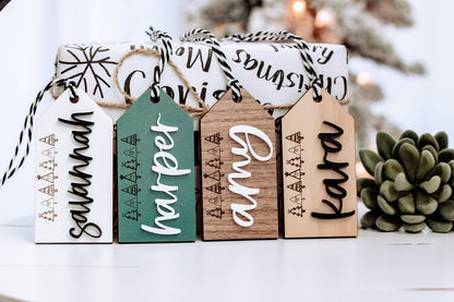 Four personalized stocking gift tags on twine in white, teal, and wood with names.