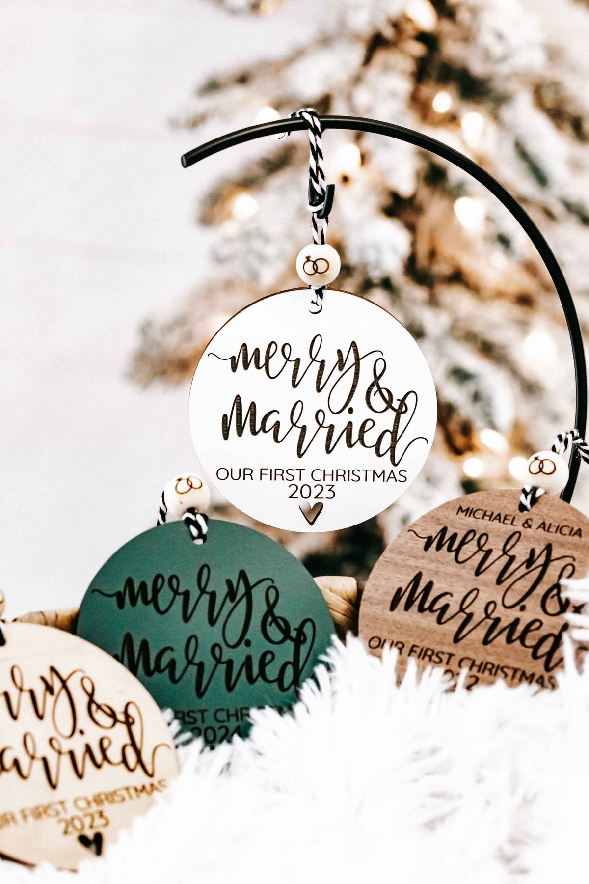 Assorted round “Merry &amp; Married” Christmas ornaments on black arched hanger with year text