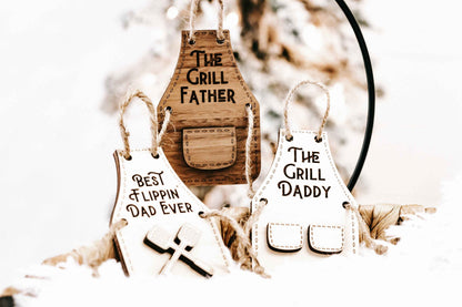 Wooden grill-themed holiday ornaments: “The Grill Father,” “Best Flippin’ Dad Ever,” and “The Grill Daddy.”