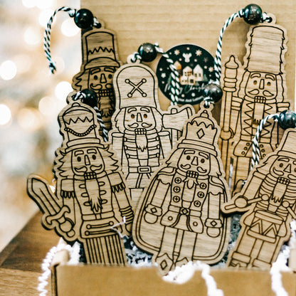 Set of 6 engraved wooden nutcracker ornaments standing in a gift box with bead hangers