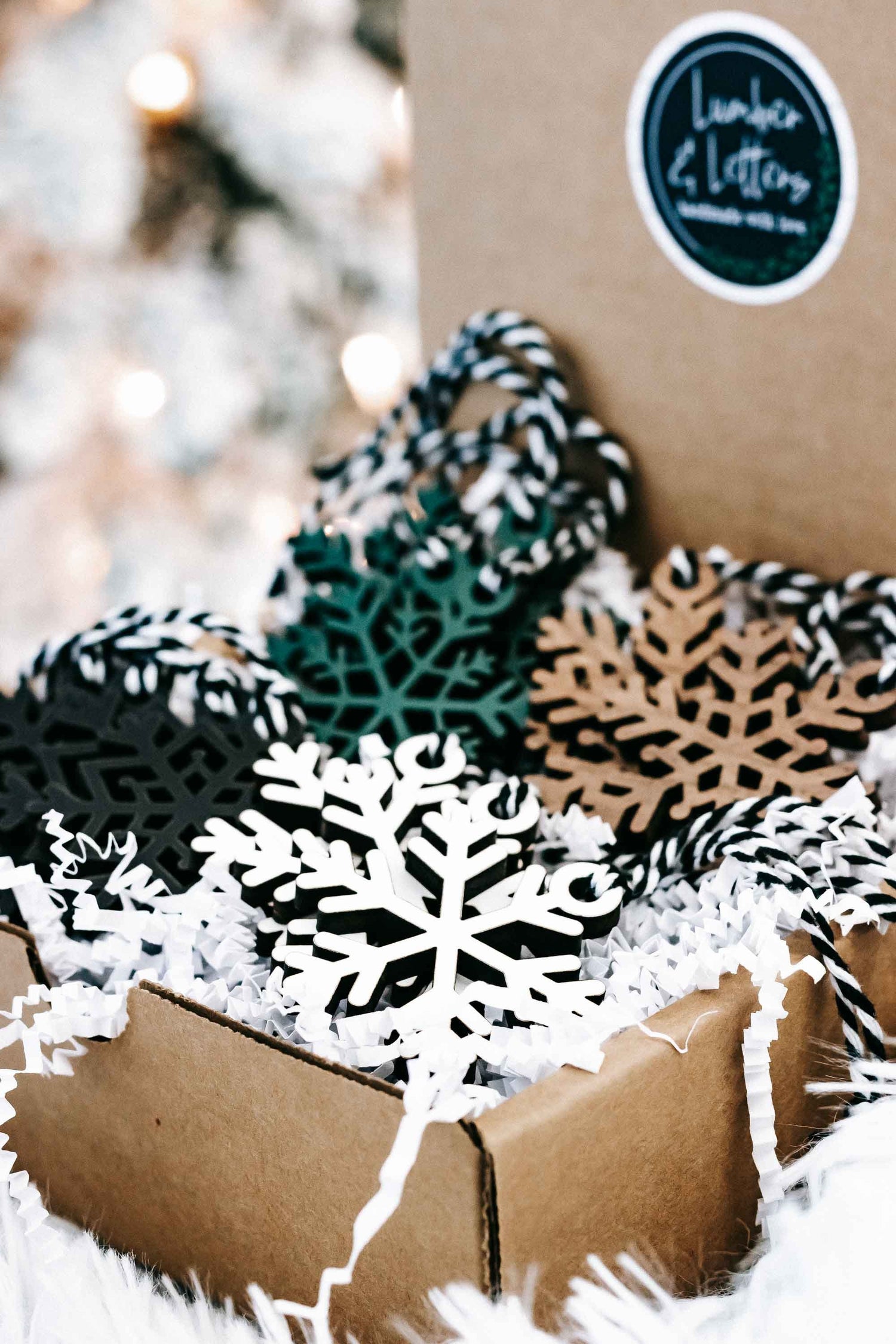 Snowflake Christmas ornament set with black, white, teal, and tan designs in a kraft box