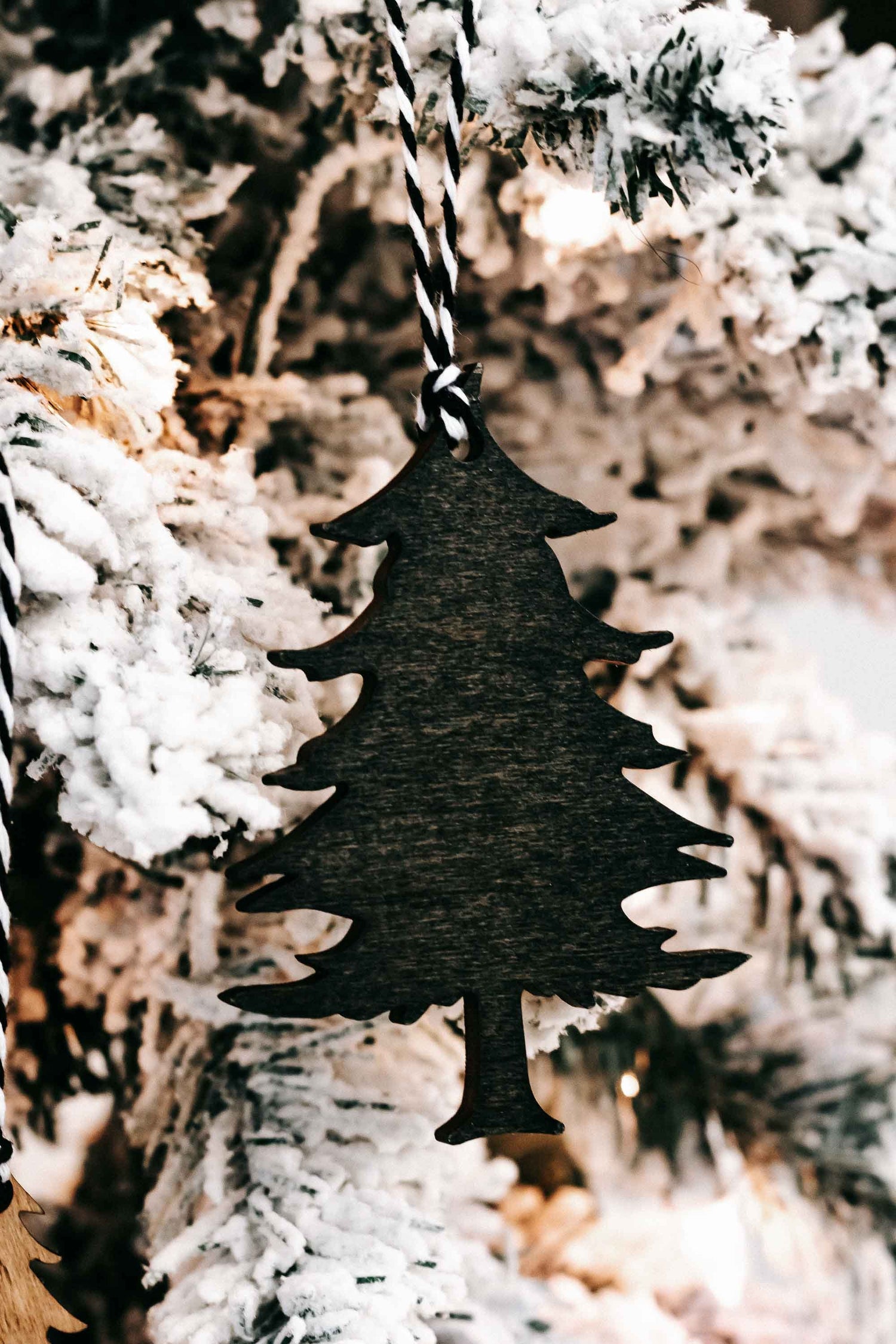 Dark green wooden Christmas tree ornament with black-and-white striped hanging loop.