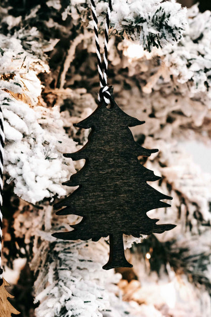 Dark green wooden Christmas tree ornament with black-and-white striped hanging loop.