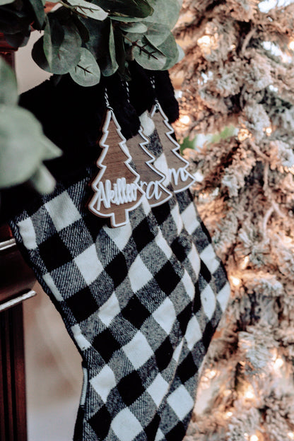 Personalized Christmas tree ornament tags hanging on buffalo plaid stocking